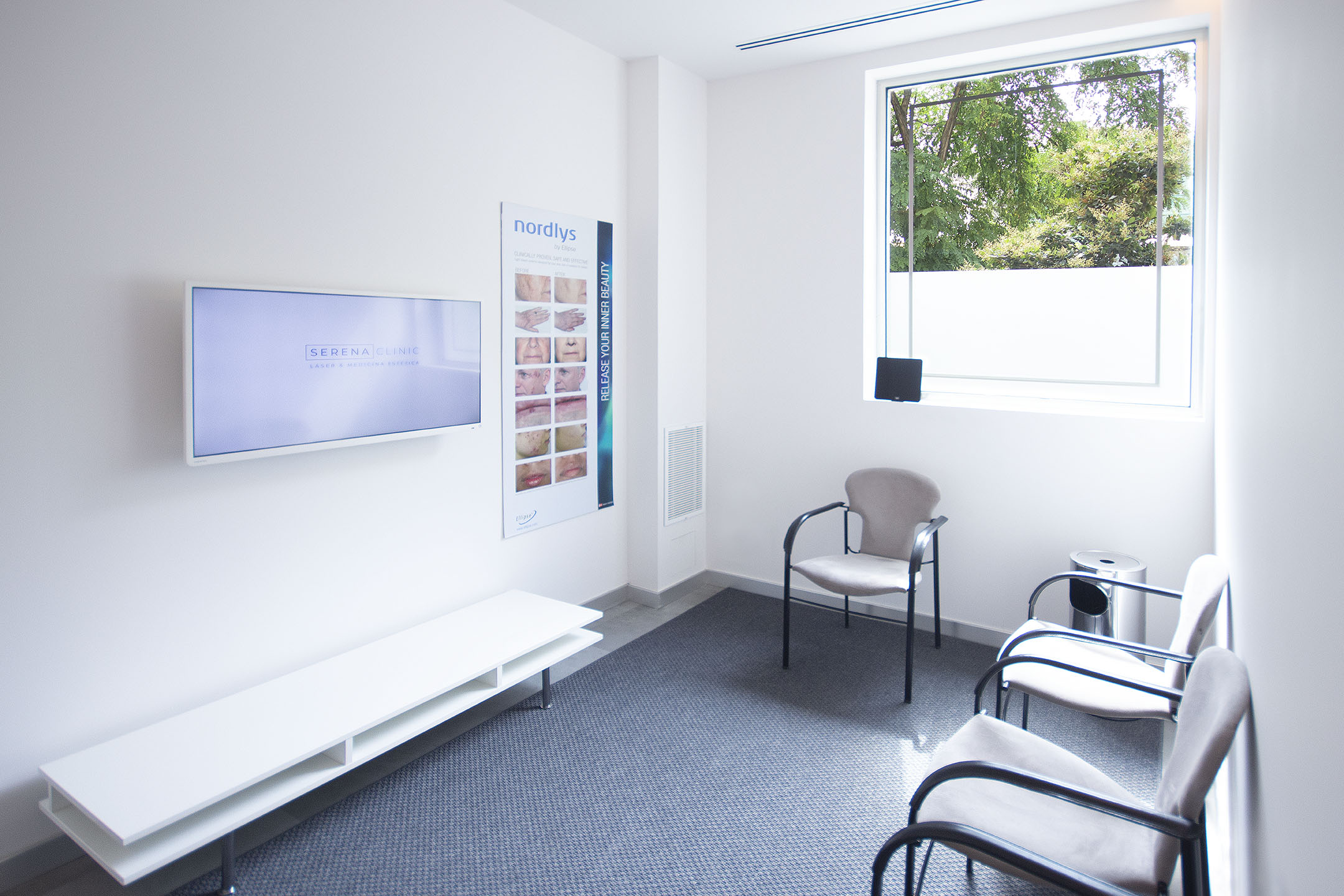 Sala de espera de Serena Clinic con la pantalla informativa de la clínica