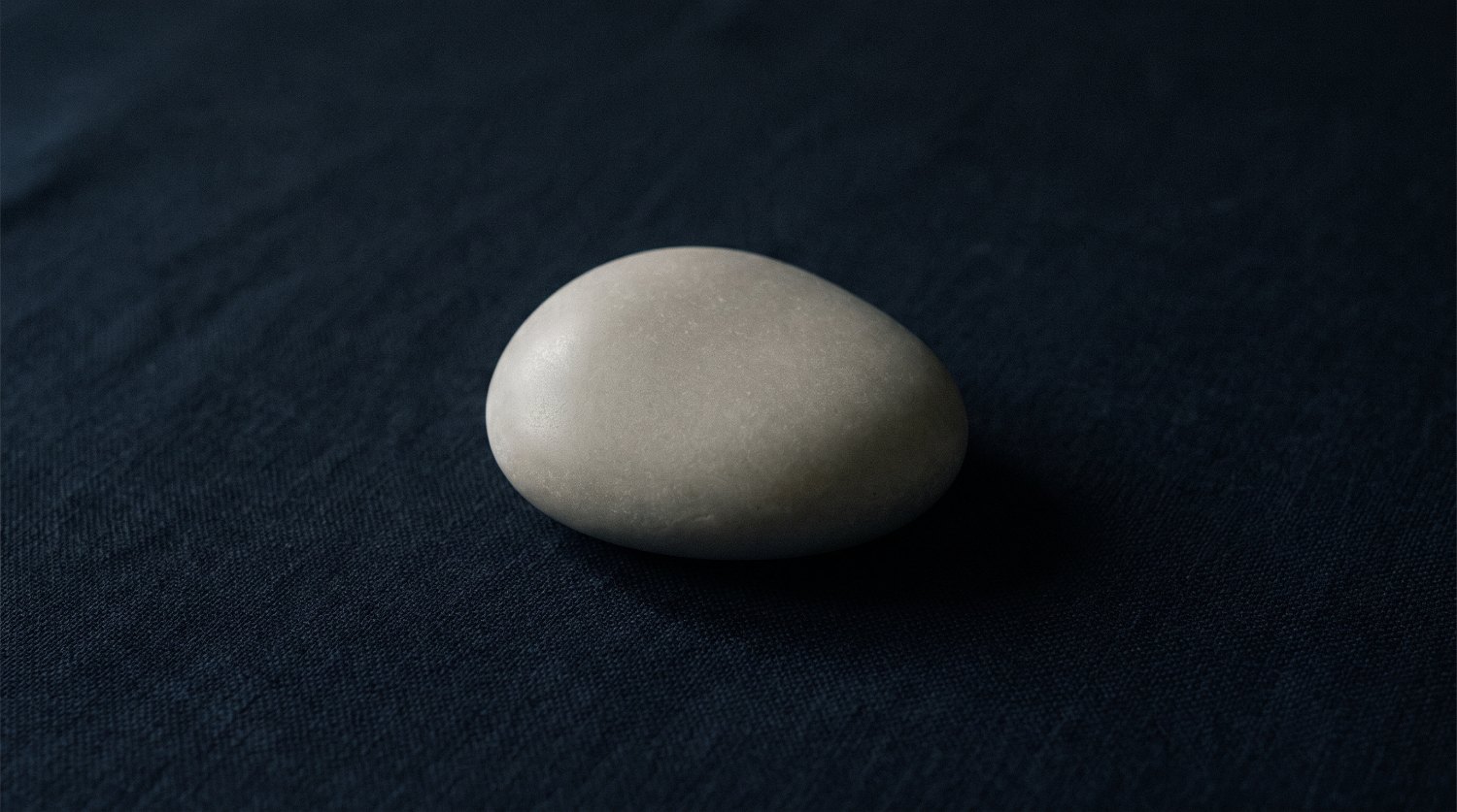Piedra clara de superficie satinada sobre fondo azul profundo, imagen ilustrativa